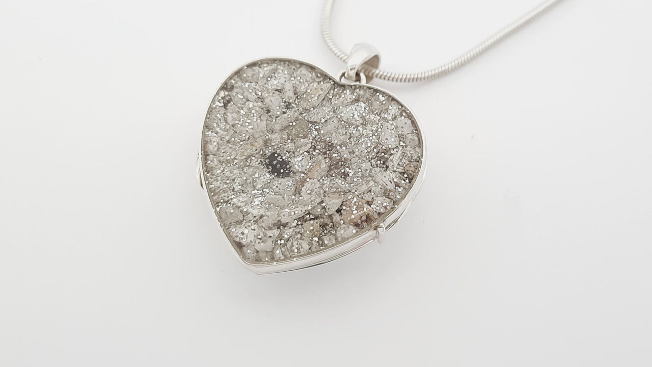 Ashes Heart-shaped silver locket video with silver glitter on a white background