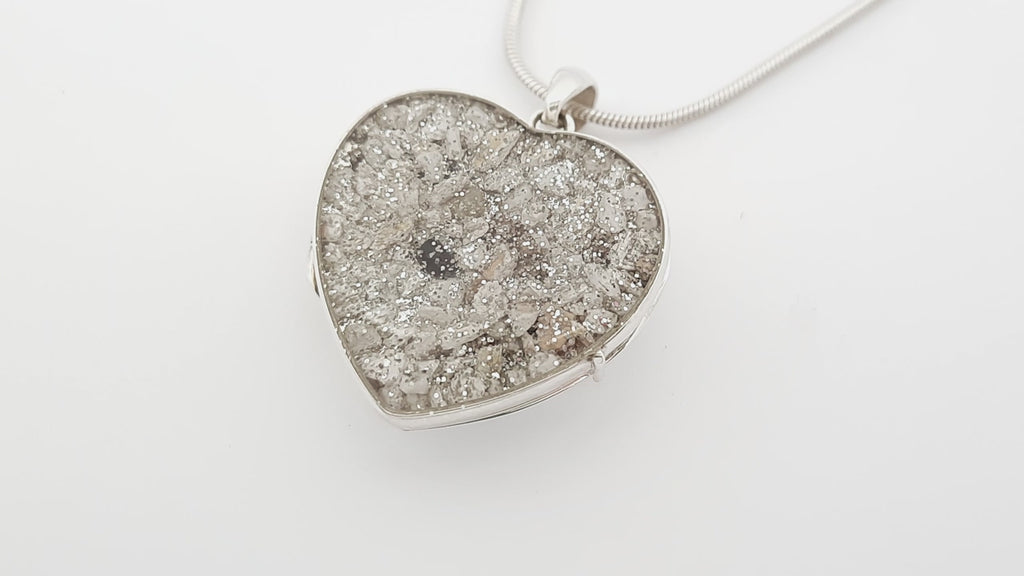 Ashes Heart-shaped silver locket video with silver glitter on a white background